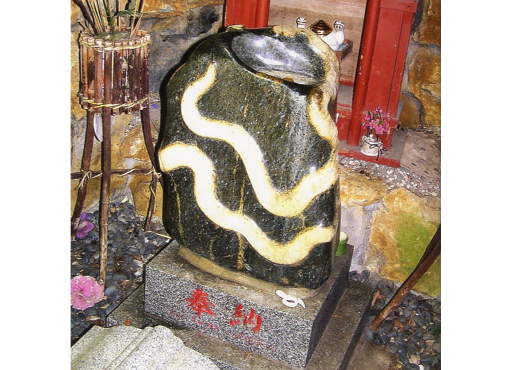 2匹のヘビが浮き出した天然石。上の窪みに洗ったお金をお供えするのだ